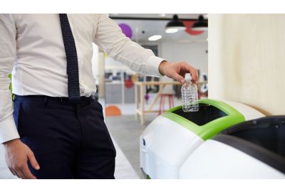 Man putting plastic bottle in recycling bin at an office.