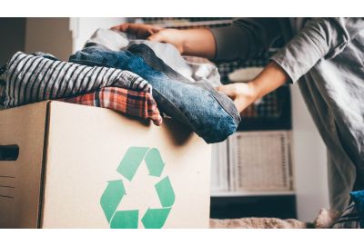Image of woman loading clothes into a cardboard box.