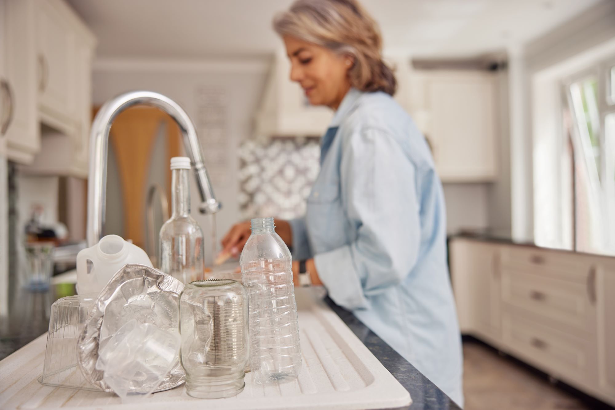 Woman rinsing out plastic bottles.